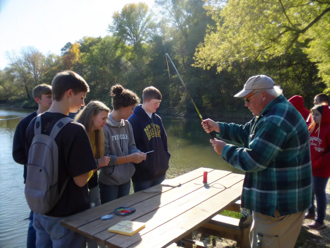 A group of children learning to tie fishing knots at a TPP12 fishing school, with an instructor demonstrating the technique.